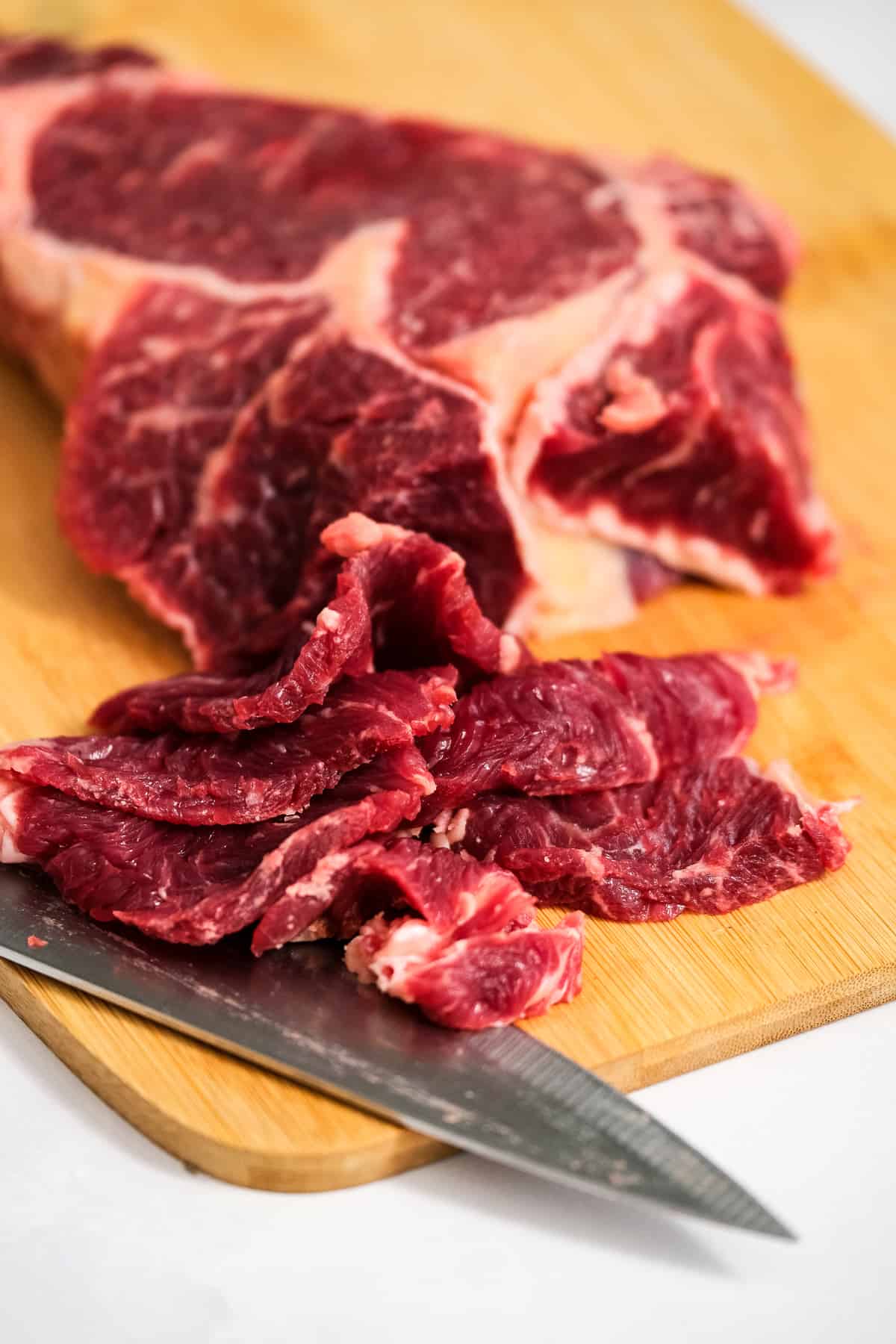 Thinly cute ribeye steak on cutting board