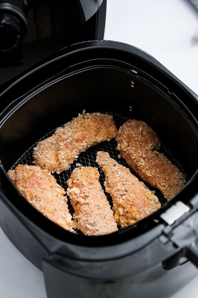 Air Fryer basket with raw chicken strips