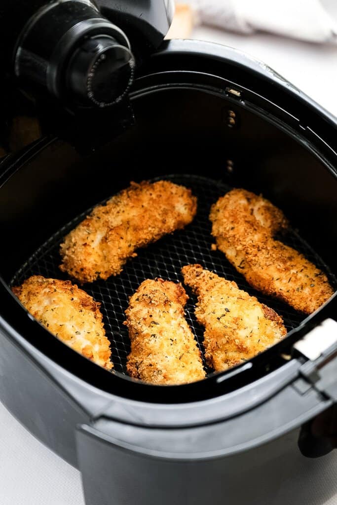 Air Fryer basket with cooked chicken strips