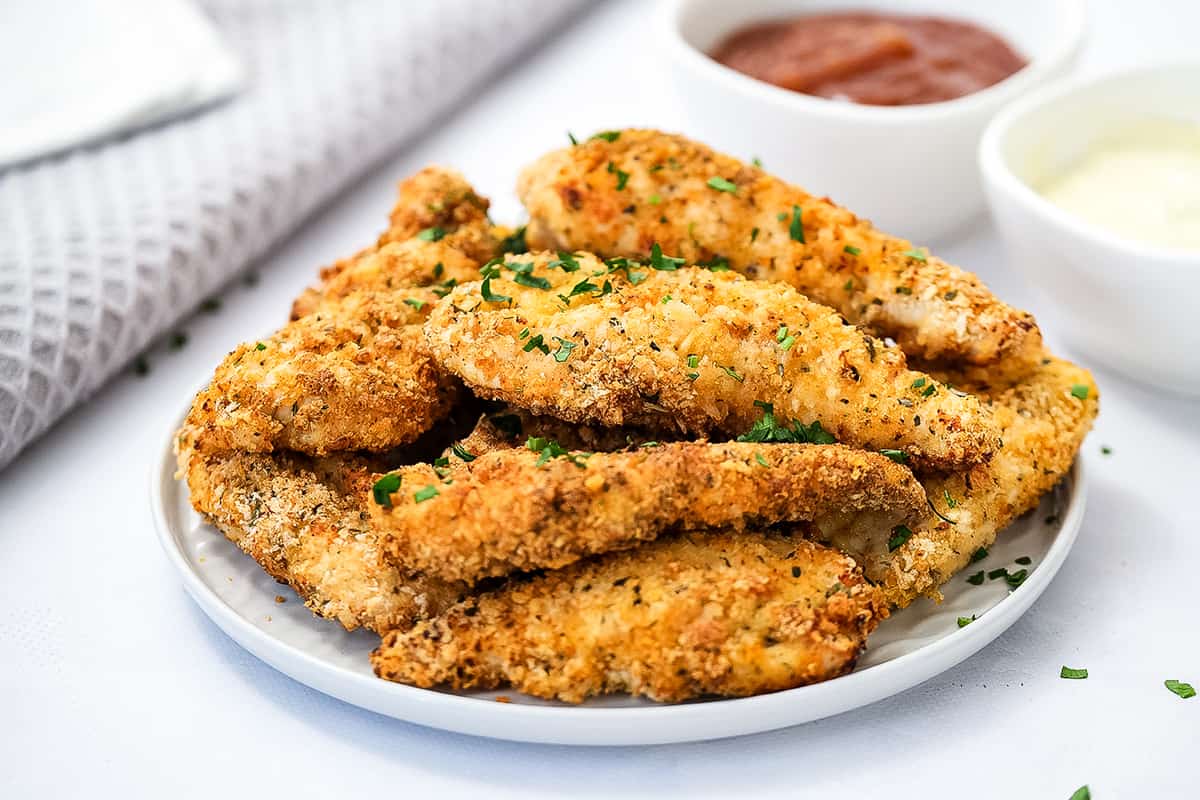 White plate with stacked chicken strips on them