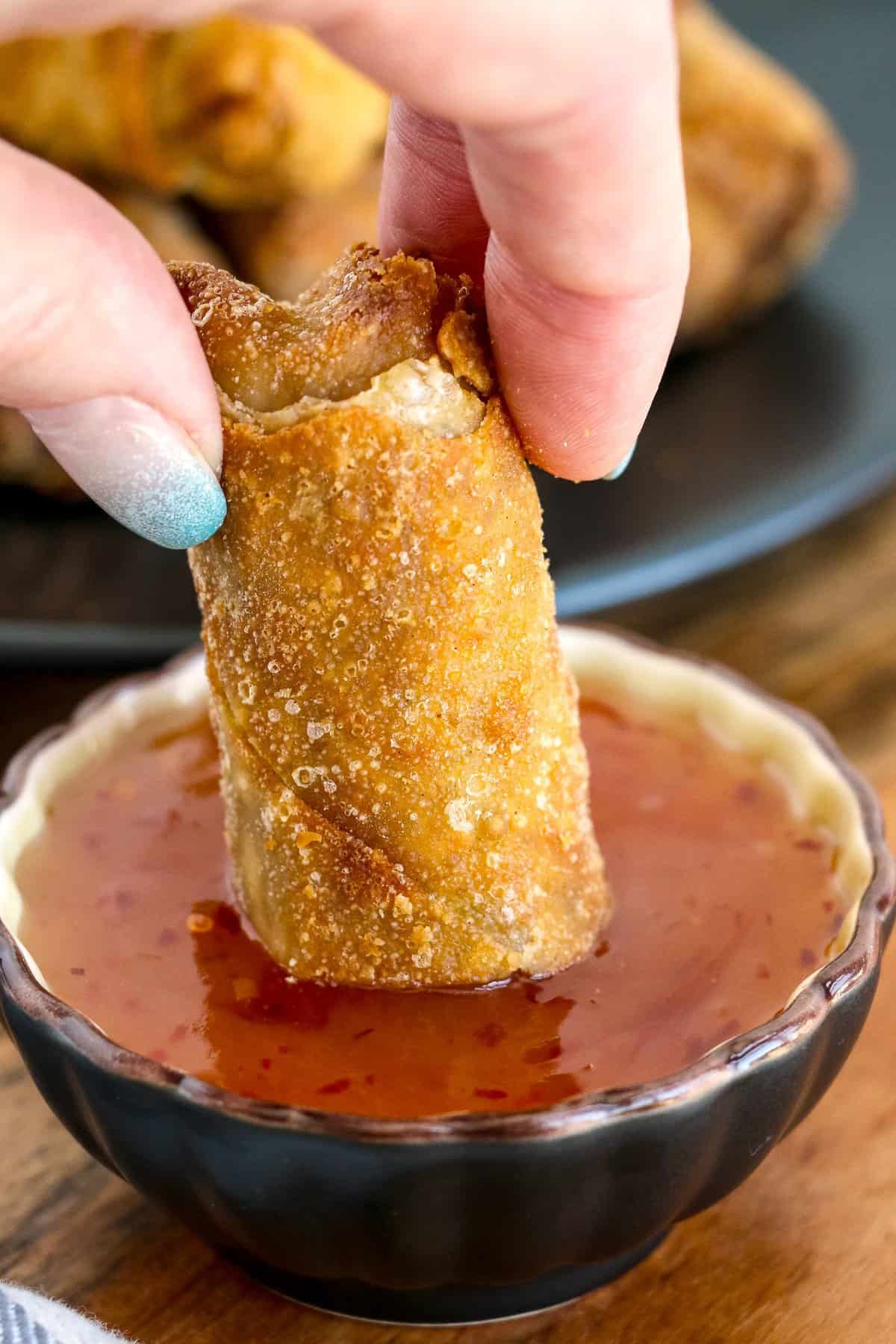 Dipping egg roll in sweet and sour sauce