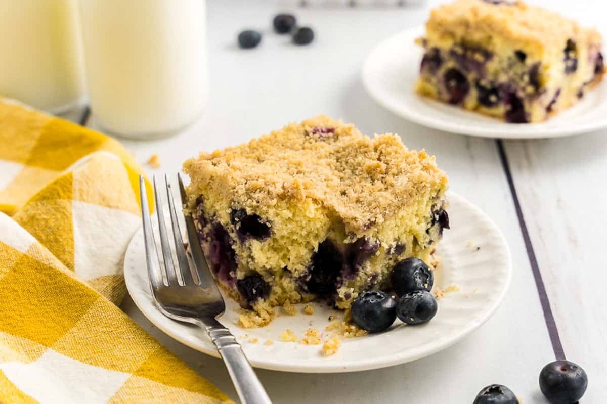 White plate with slice of blueberry coffee cake on it