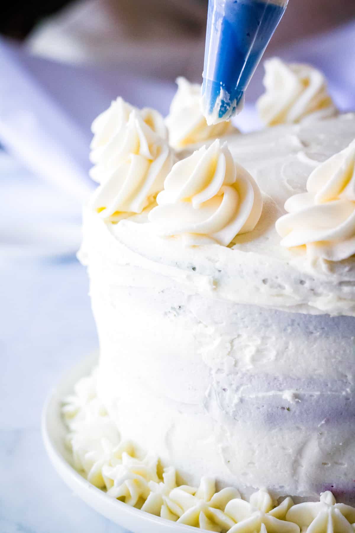 Piping butter cream onto two tiered cake