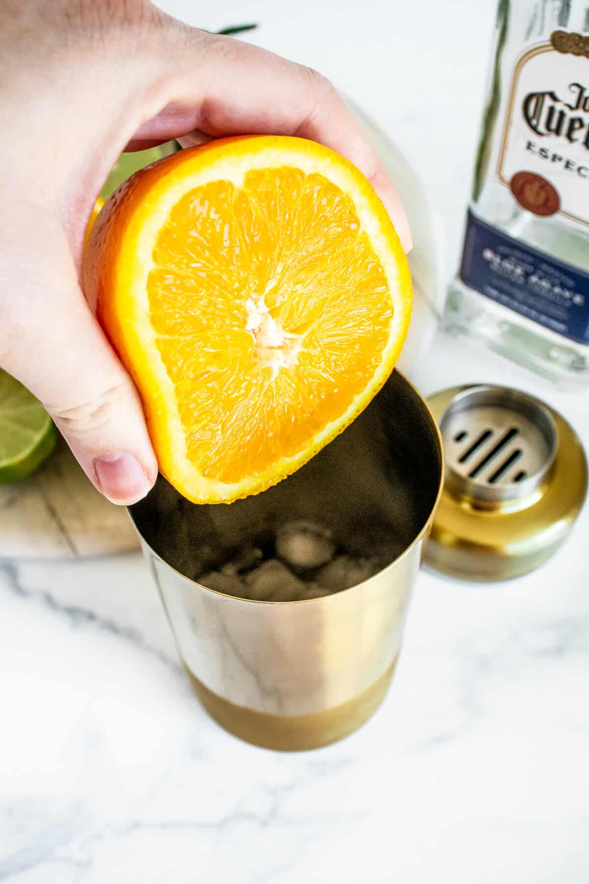 Squeezing orange into cocktail shaker.