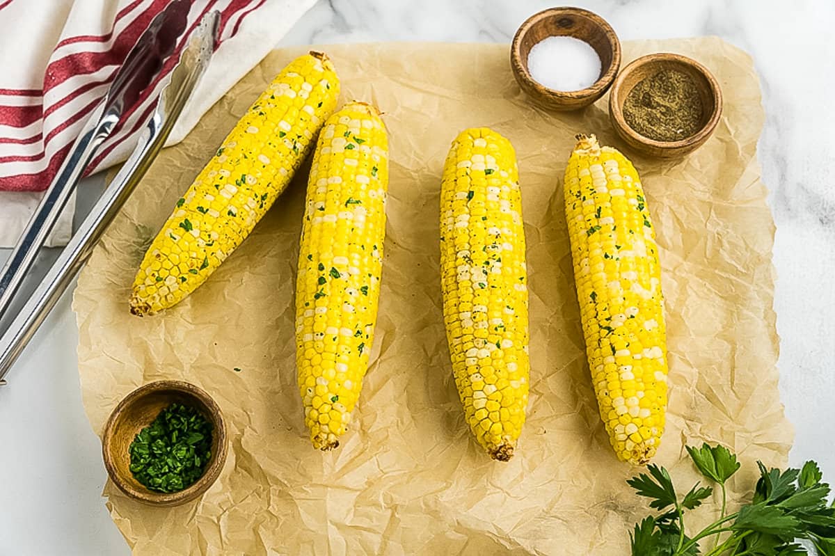 Four pieces of corn on the cob on brown parchment paper