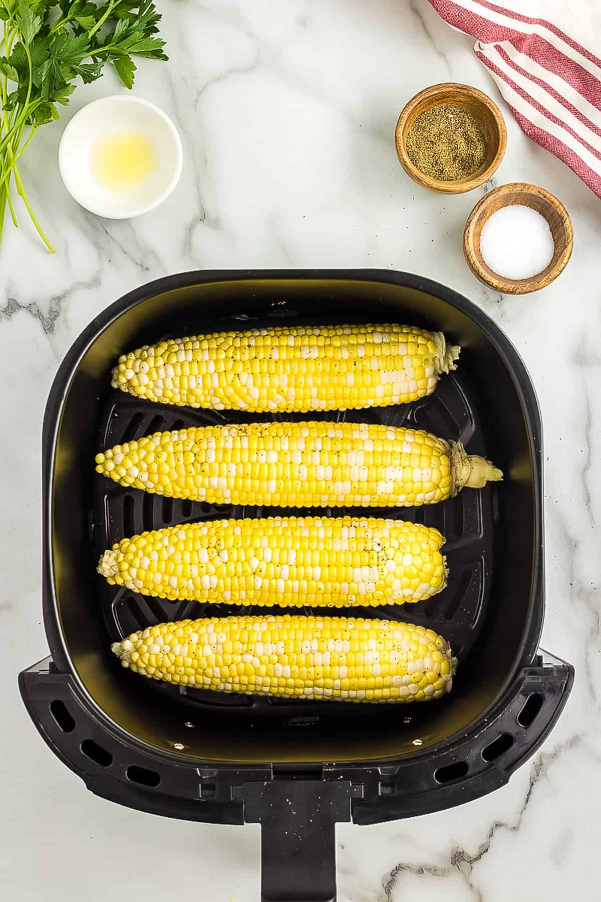 Four pieces of corn in air fryer basket
