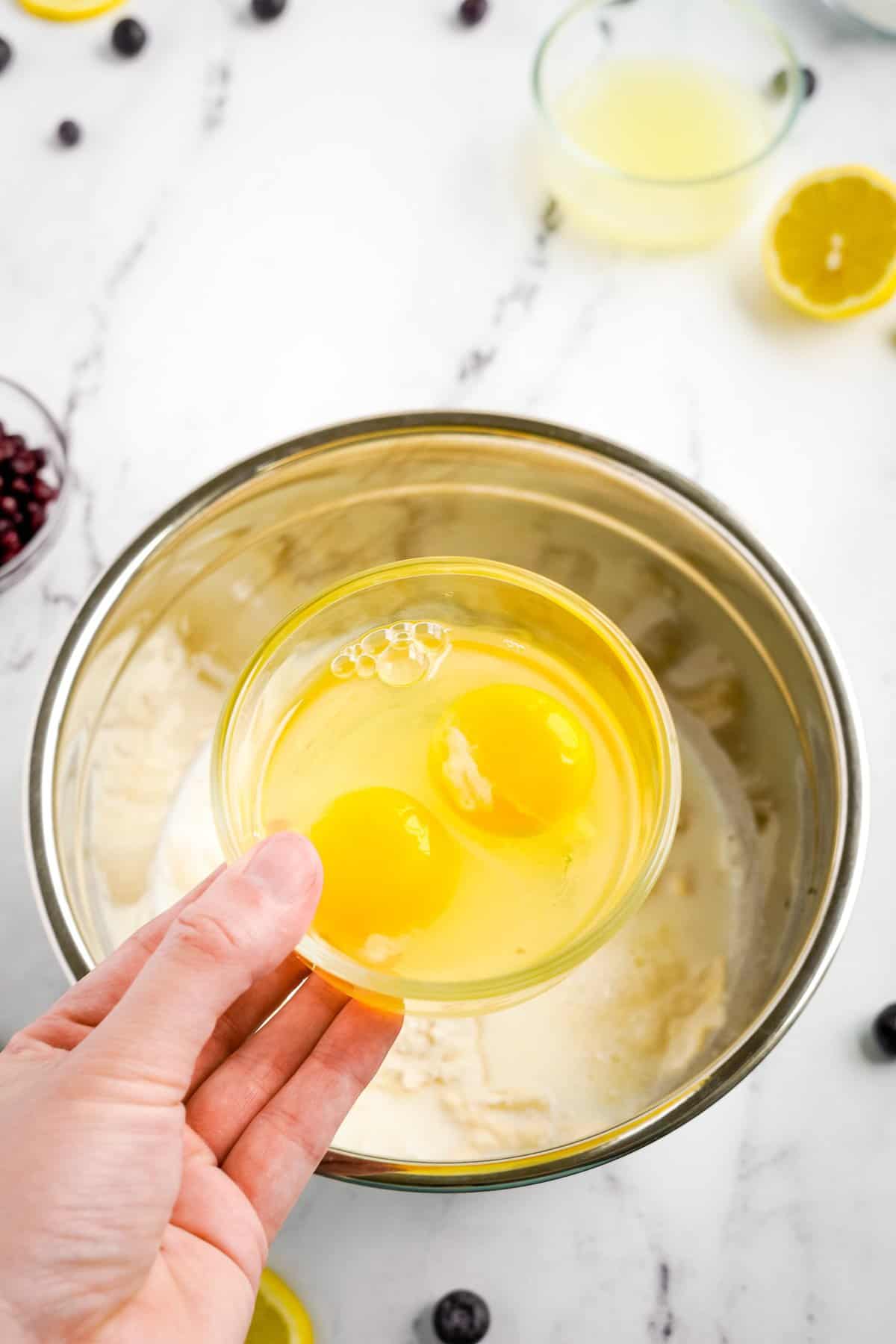 adding eggs to muffin bread mix in bowl