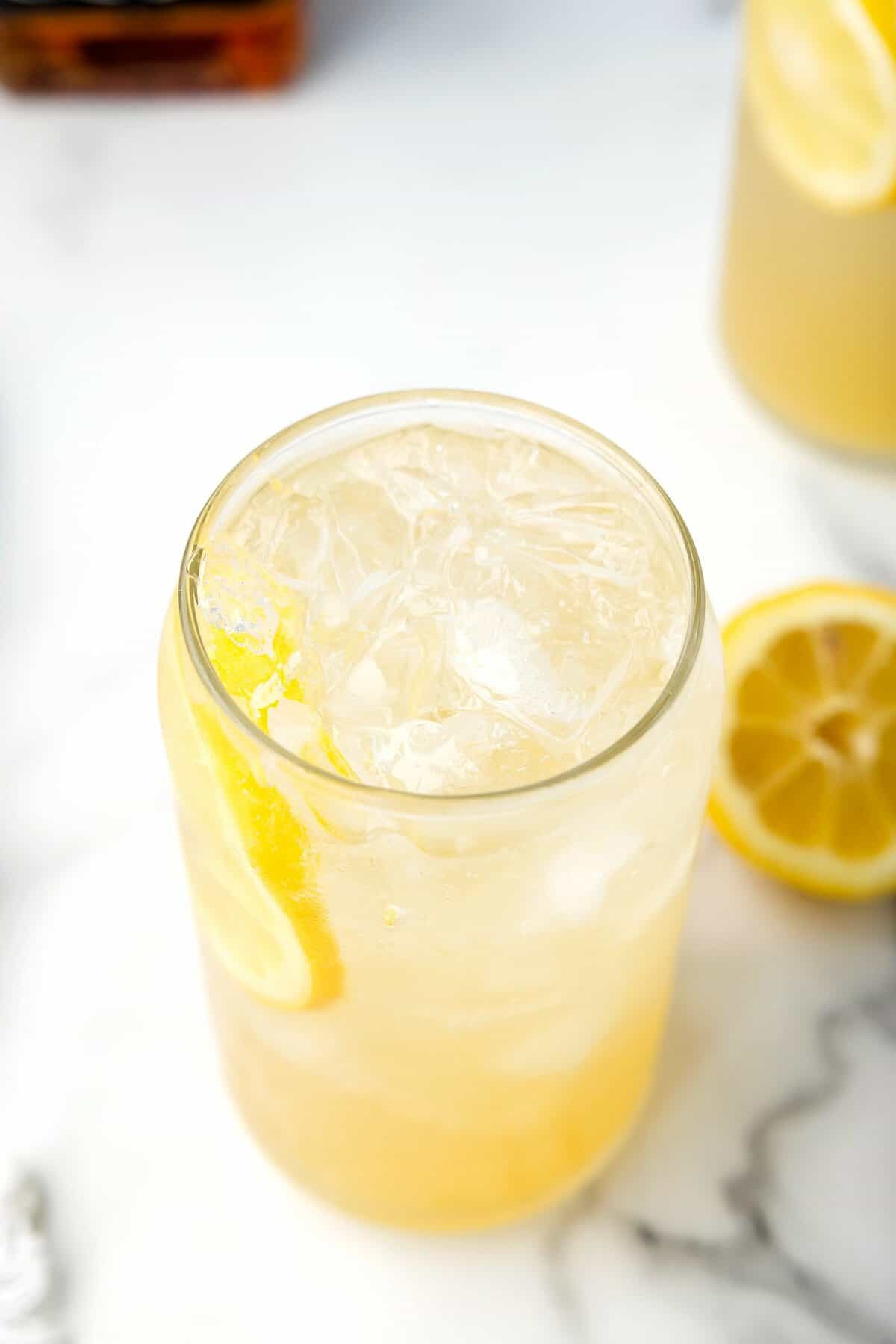 Glass with ice, lemon slices and whiskey lemonade