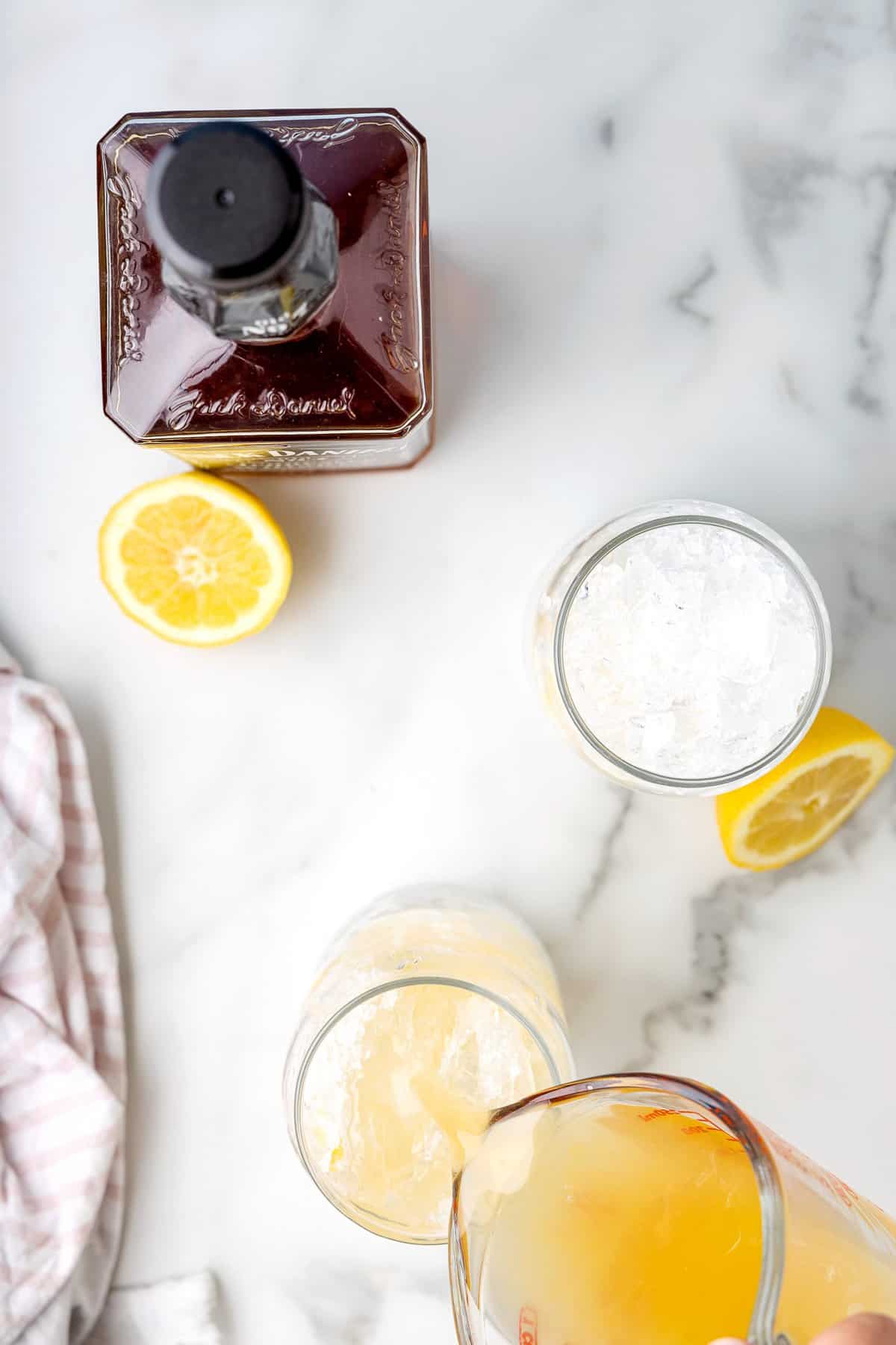 Pouring whiskey lemonade into glass with ice