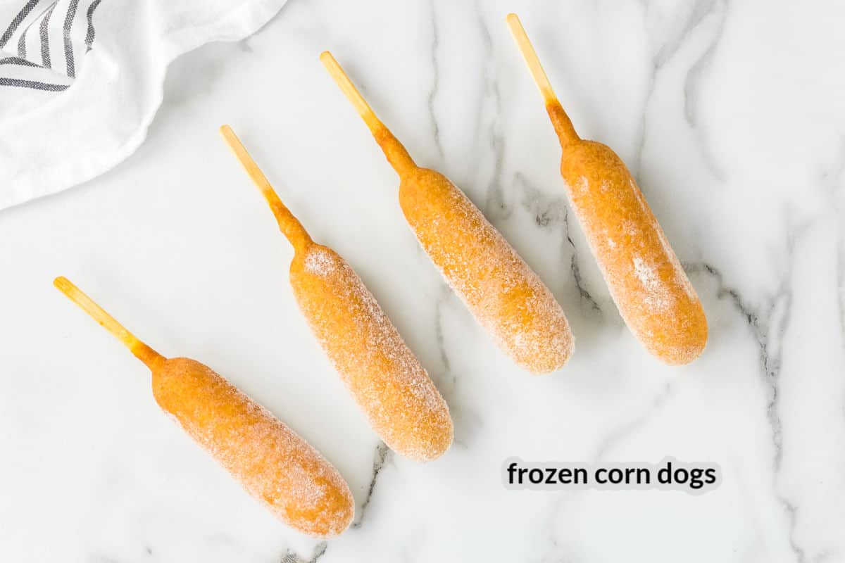 Four frozen corn dogs on marble background