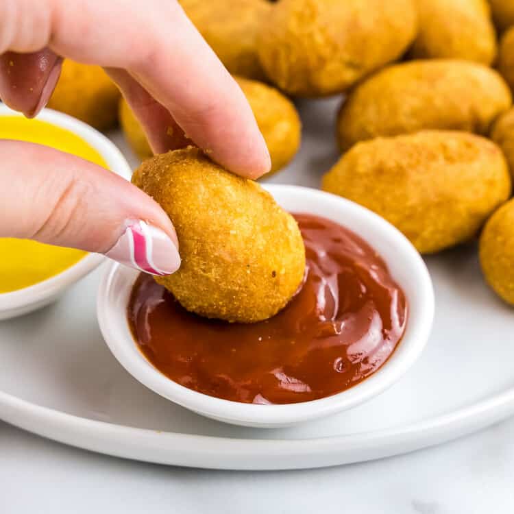 Dipping mini corn dog into ketchup