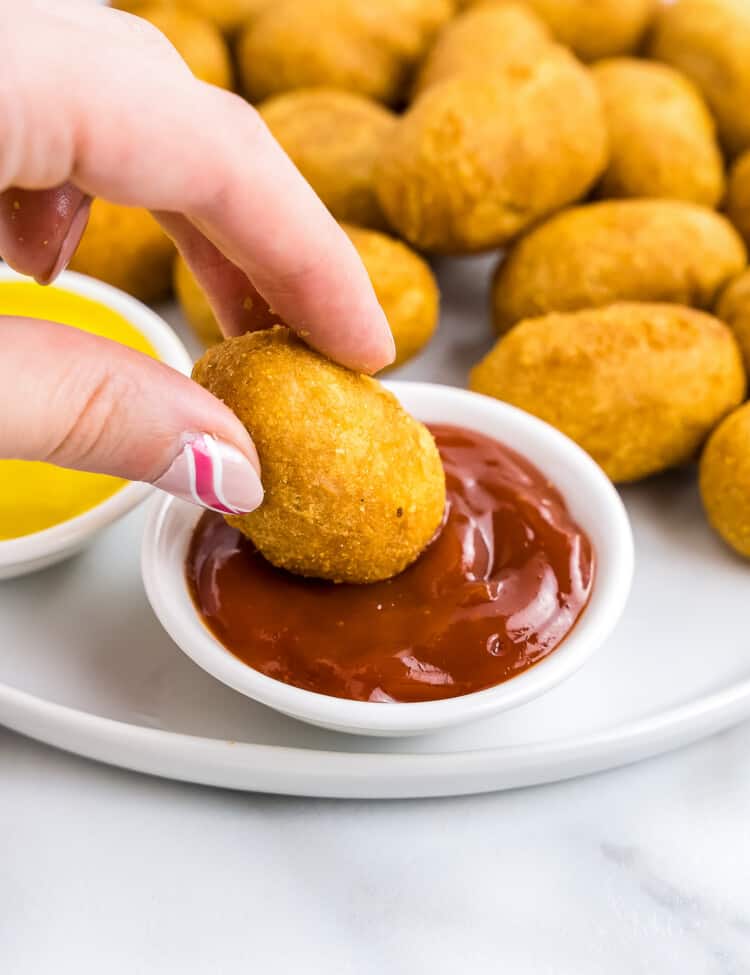 Dipping mini corn dog into ketchup