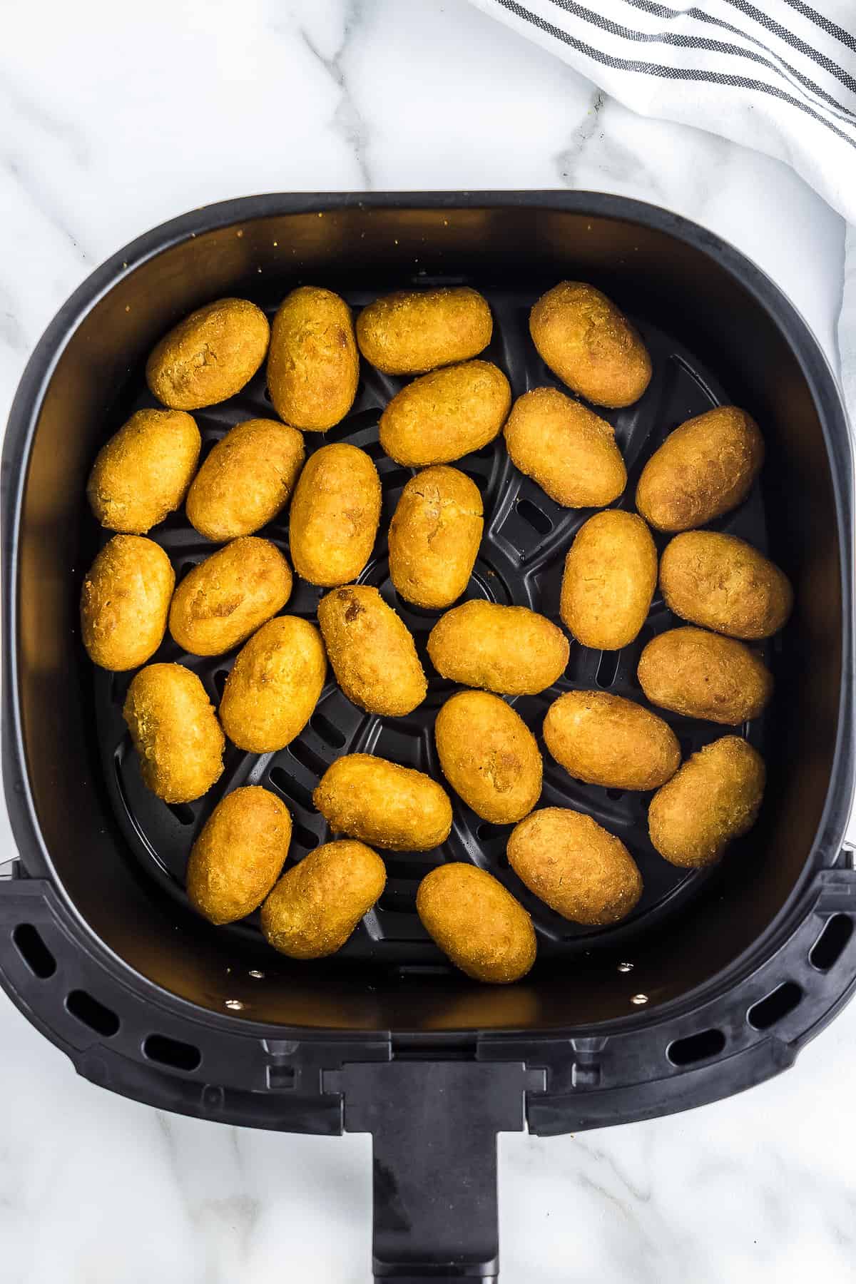 Cooked mini corn dogs in air fryer basket