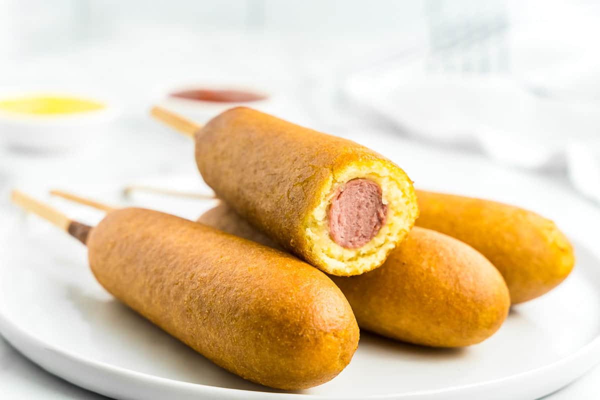 white plate with four corn dogs on it