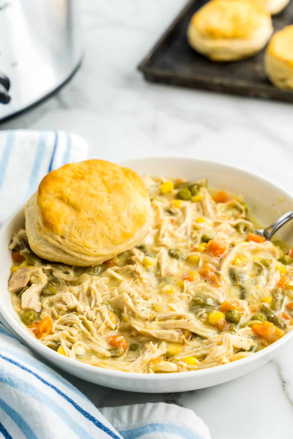 White bowl with chicken pot pie and biscuit