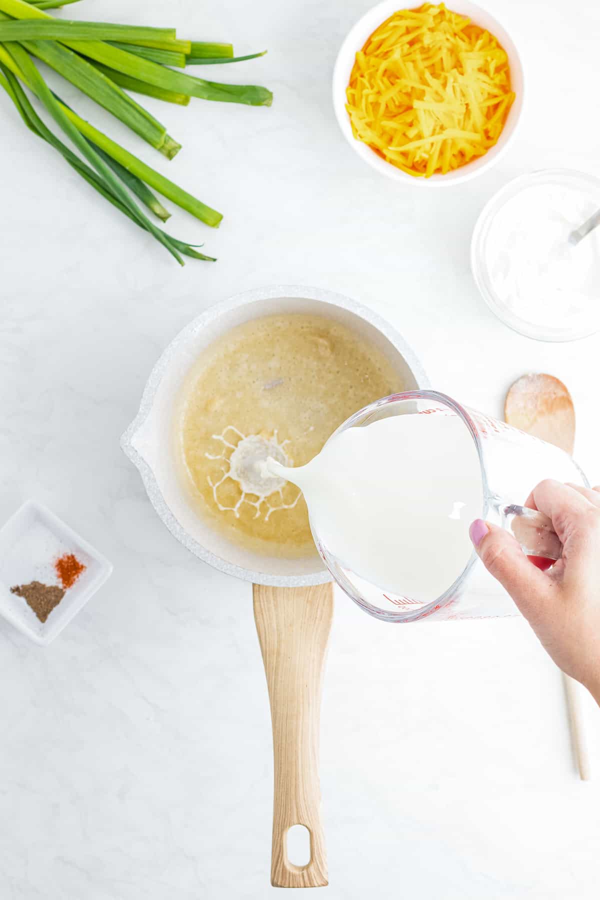 Pouring milk into saucepan to make roux