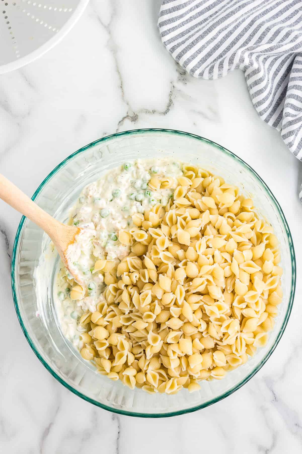 Stirring shell pasta in macaroni salad