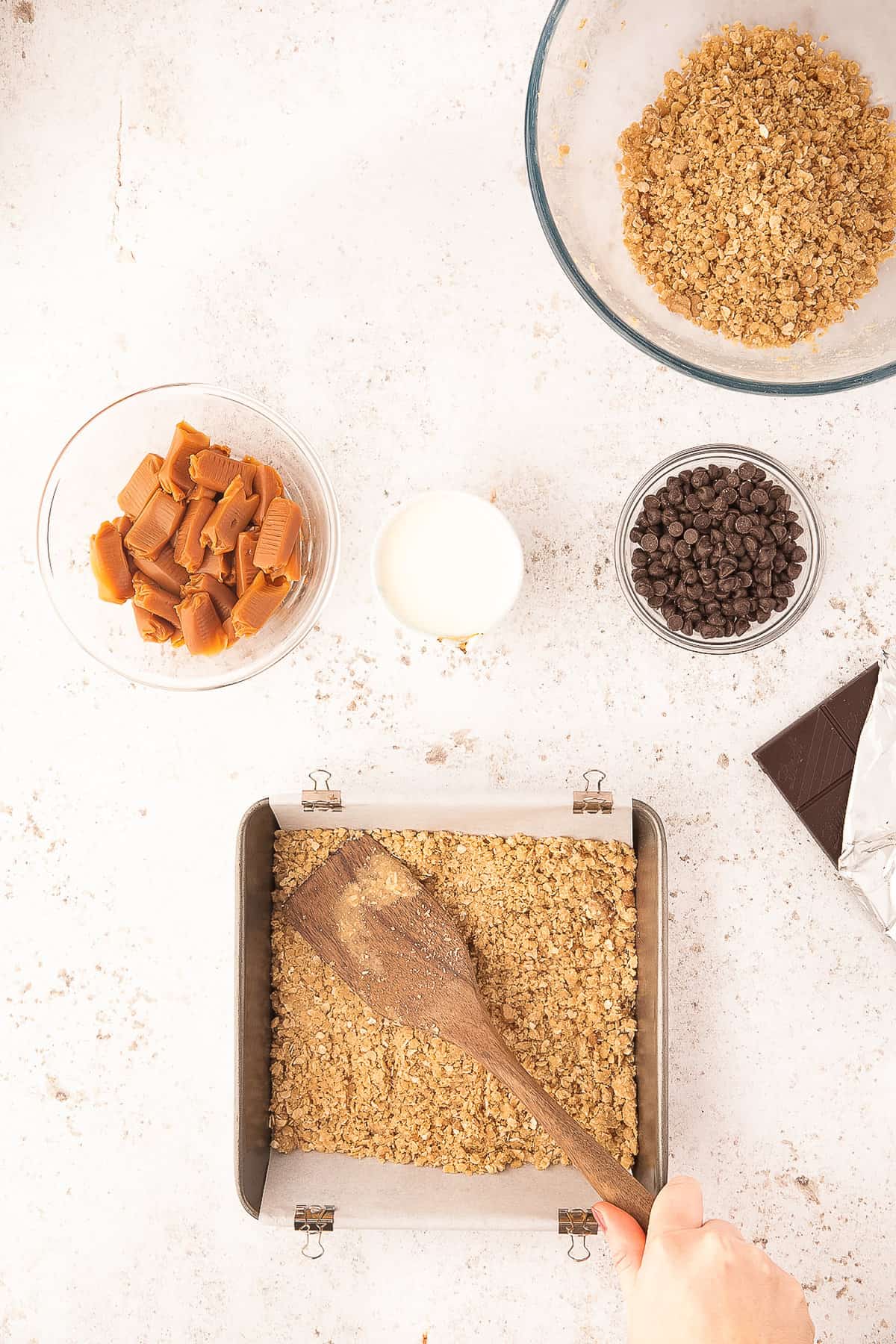 Pressing oat crust into square baking dish