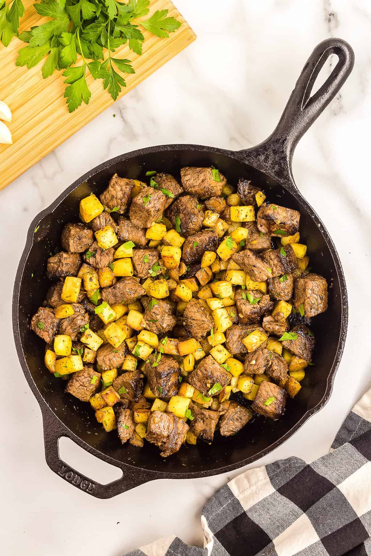 Cast iron skillet with garlic butter steak and potatoes