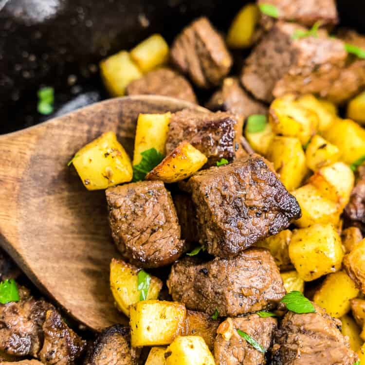 Wooden spoon with steak and potatoes
