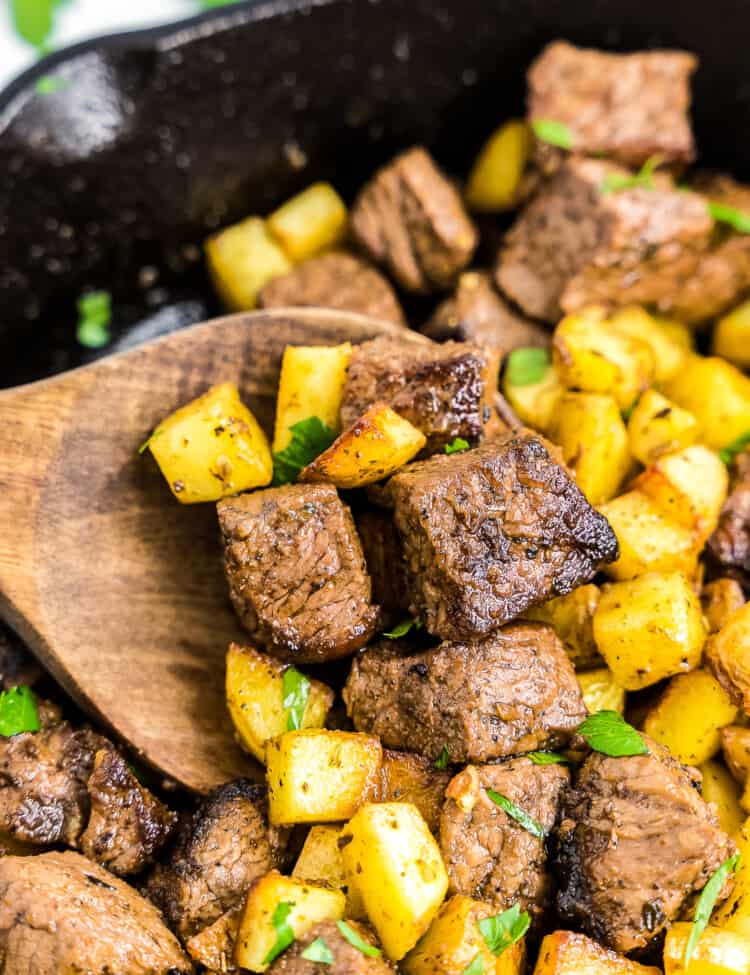 Wooden spoon with steak and potatoes