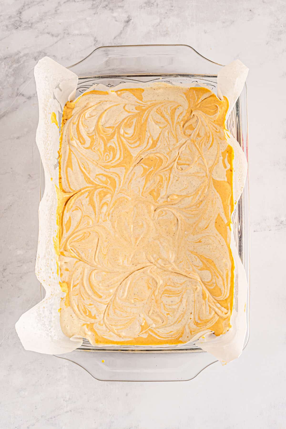 Baking dish with pumpkin pie cheesecake swirled together in it before baking