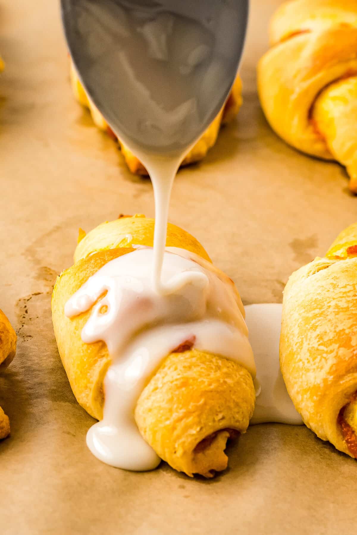 Drizzling powdered sugar glaze on crescent roll