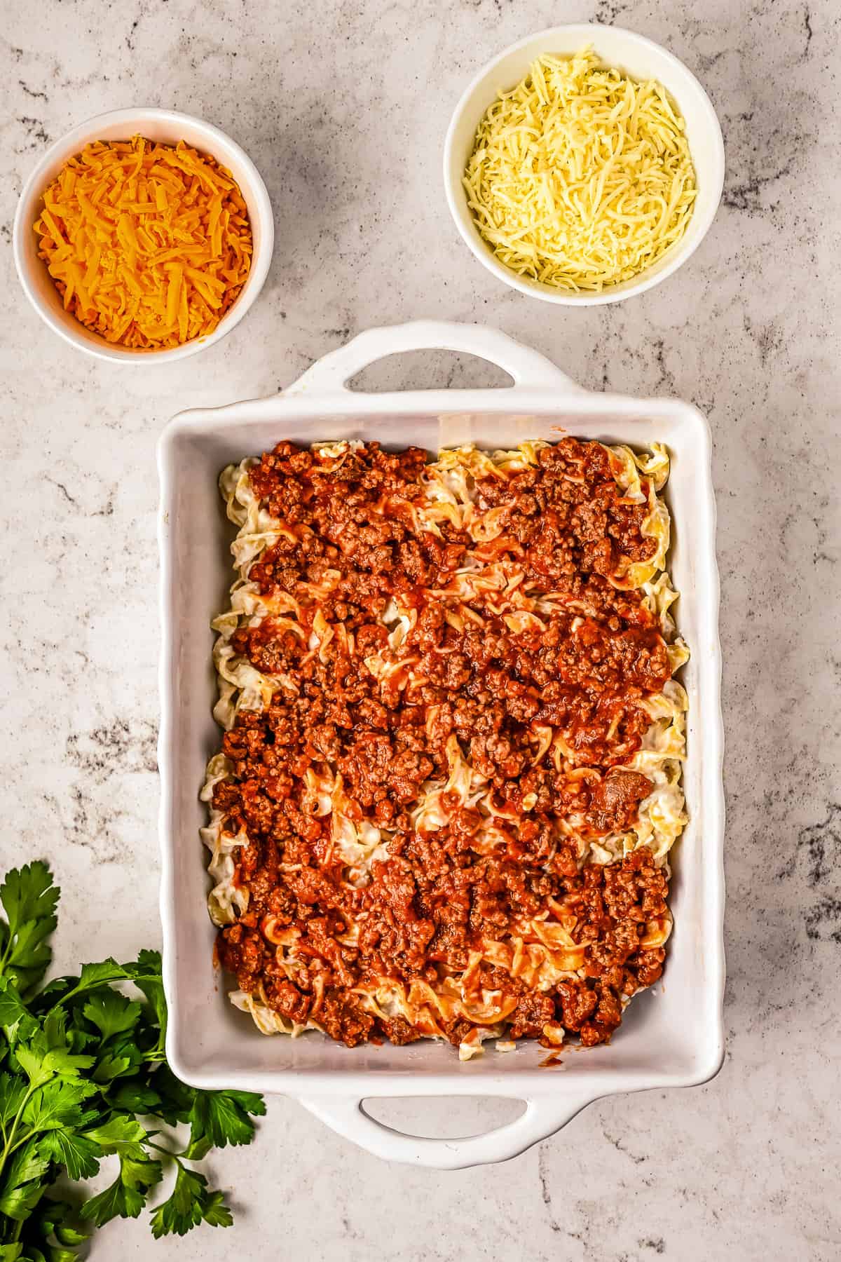 White baking dish with egg noodles and beef sauce