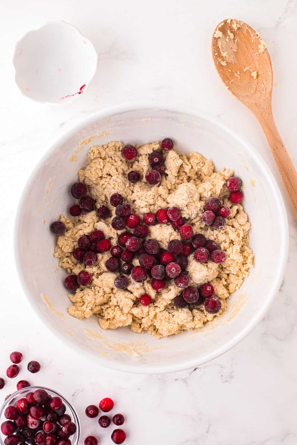 Scone dough in mixing bowl with frozen cranberries on top