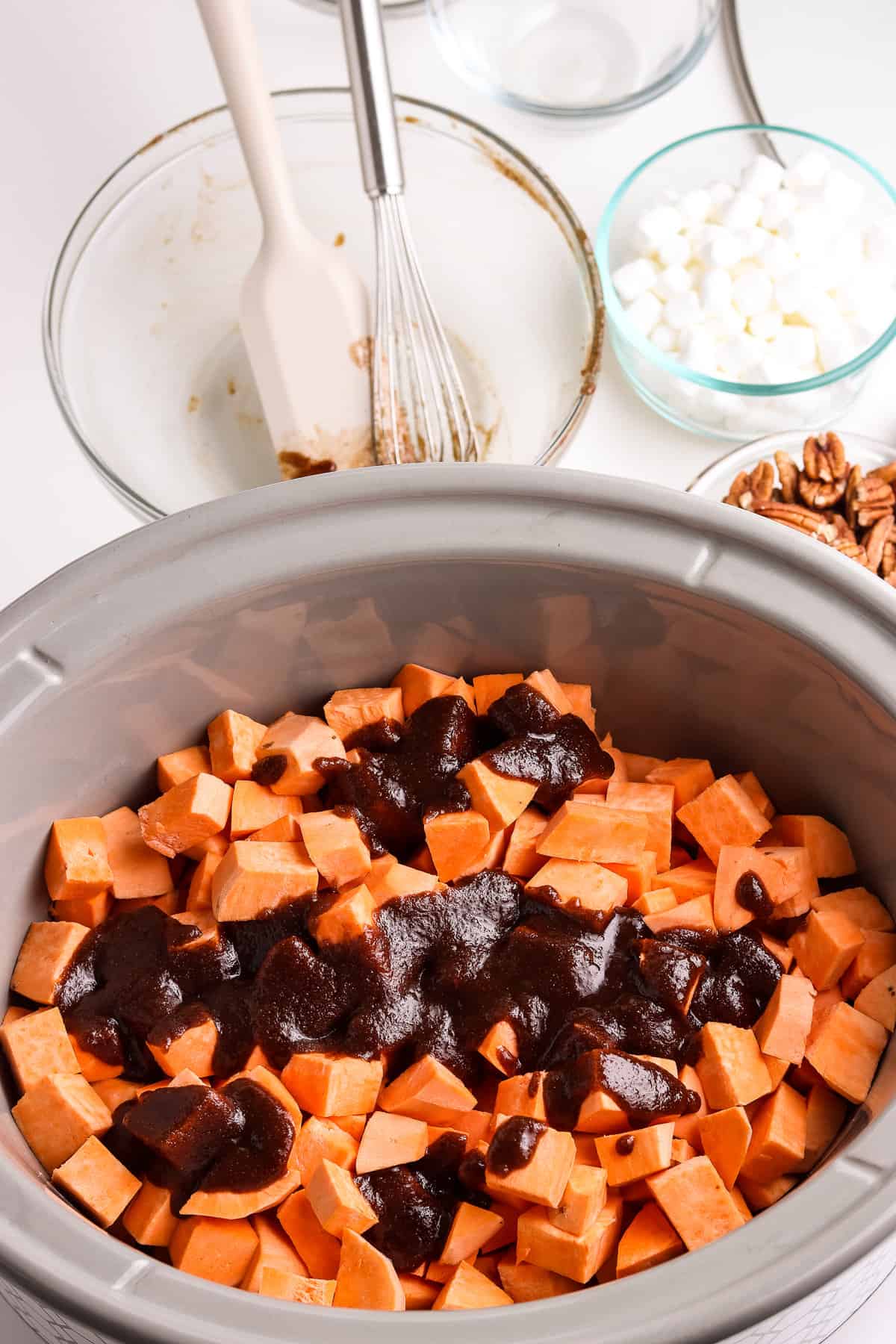 Crock Pot with cut up sweet potatoes drizzled with butter brown sugar topping