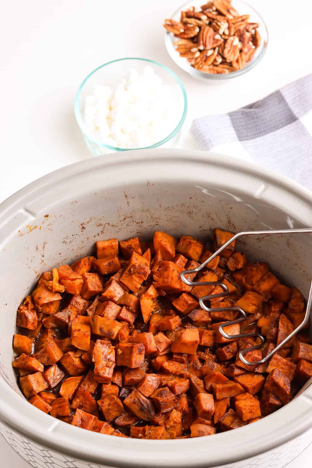 Crock Pot with cooked sweet potatoes drizzled with butter brown sugar topping
