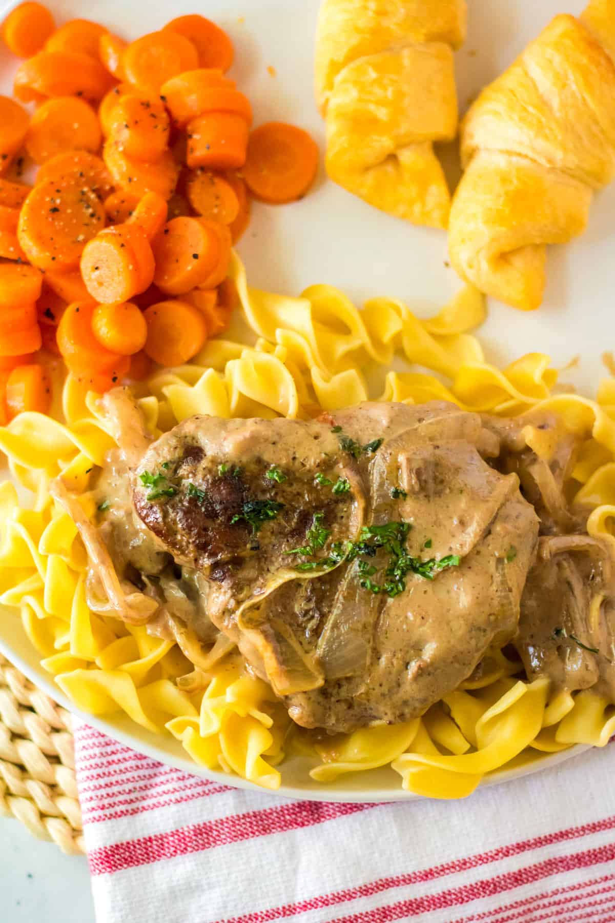 Cube steak served over a bed of egg noodles on white plate