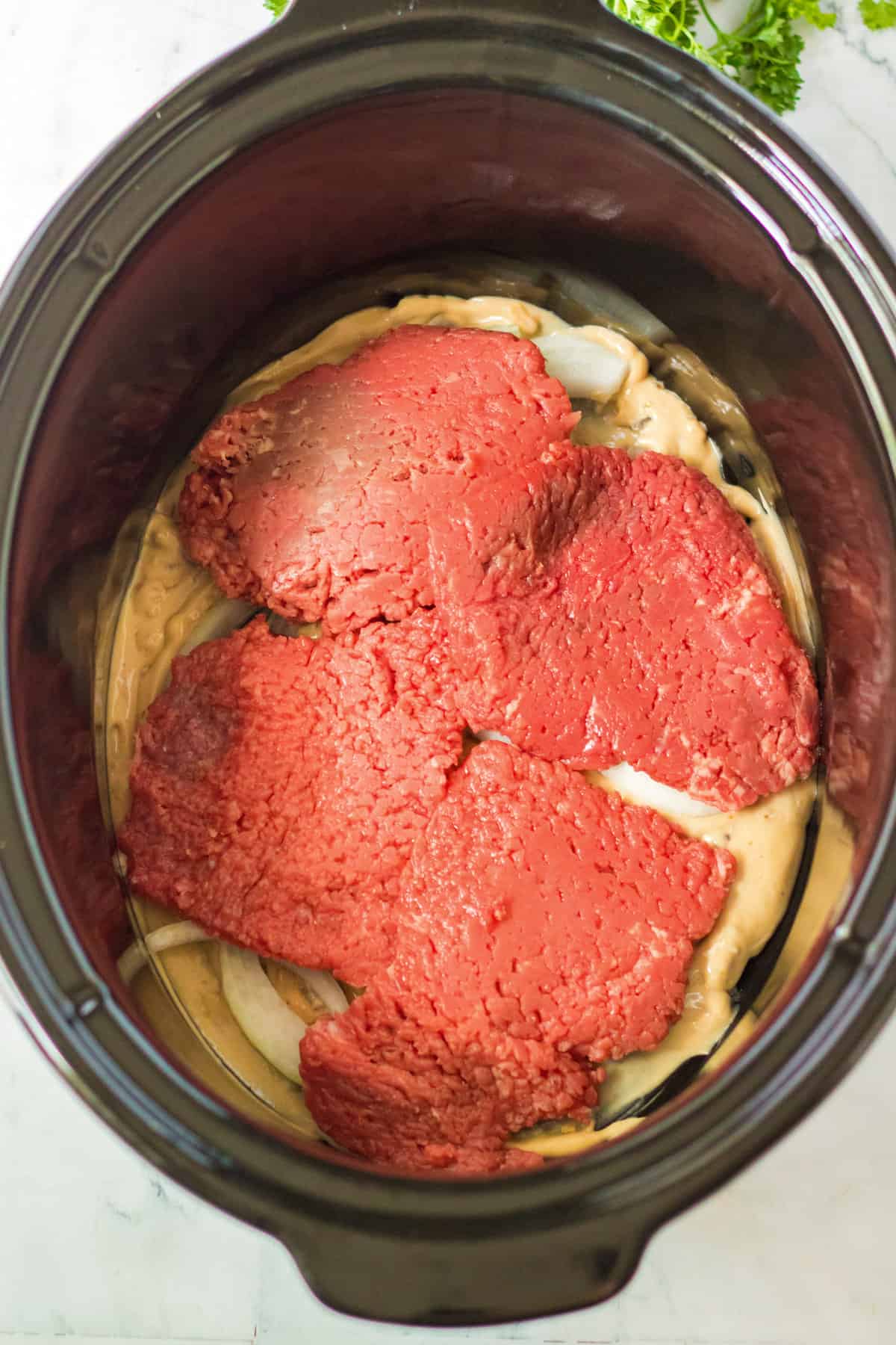 Black crock pot with cream of mushroom soup and cube steak