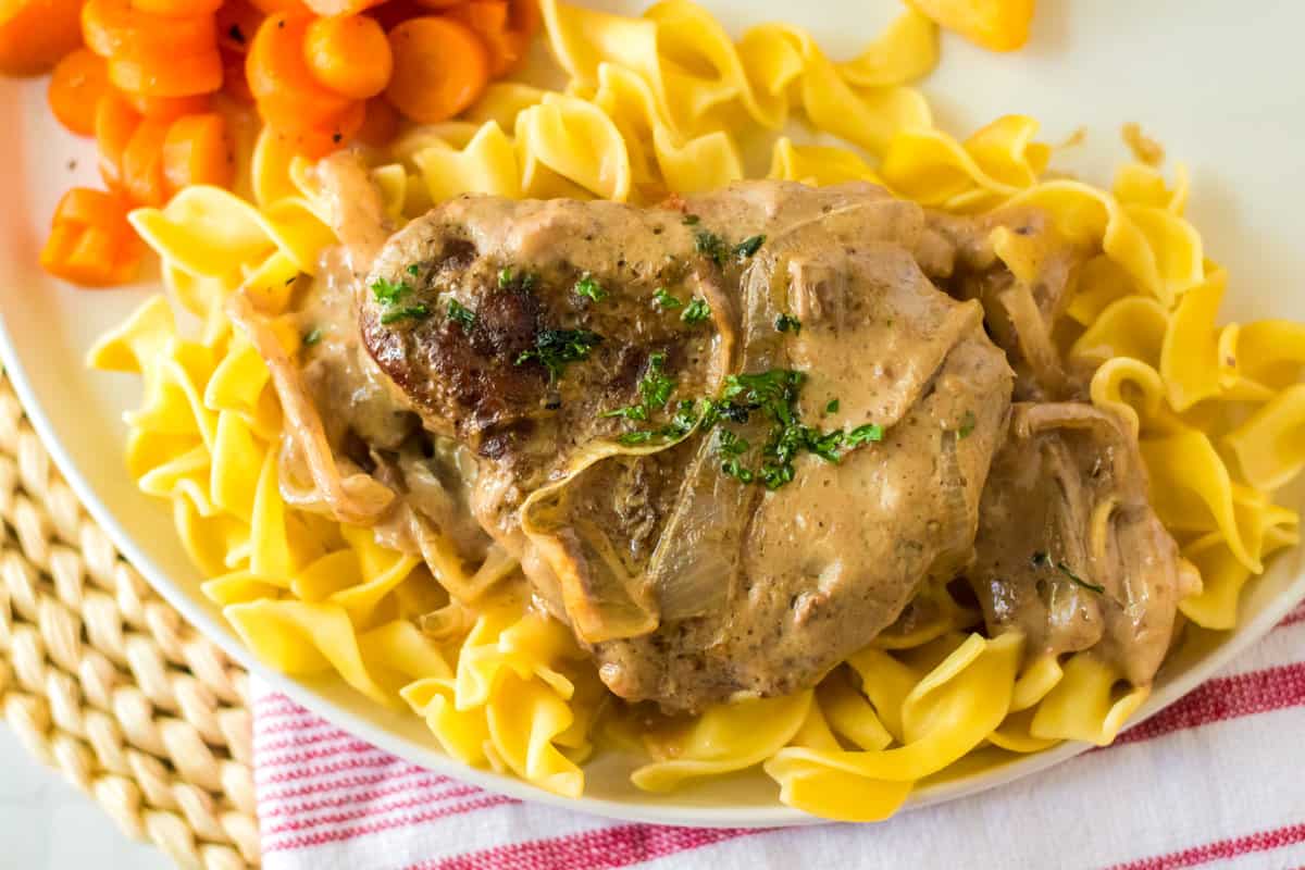 White plate with egg noodles and cube steak and gravy