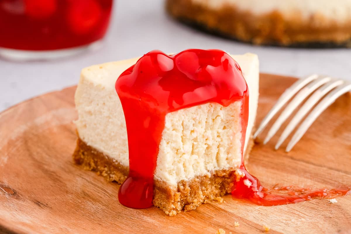 Slice of cheesecake with bite gone on wood plate
