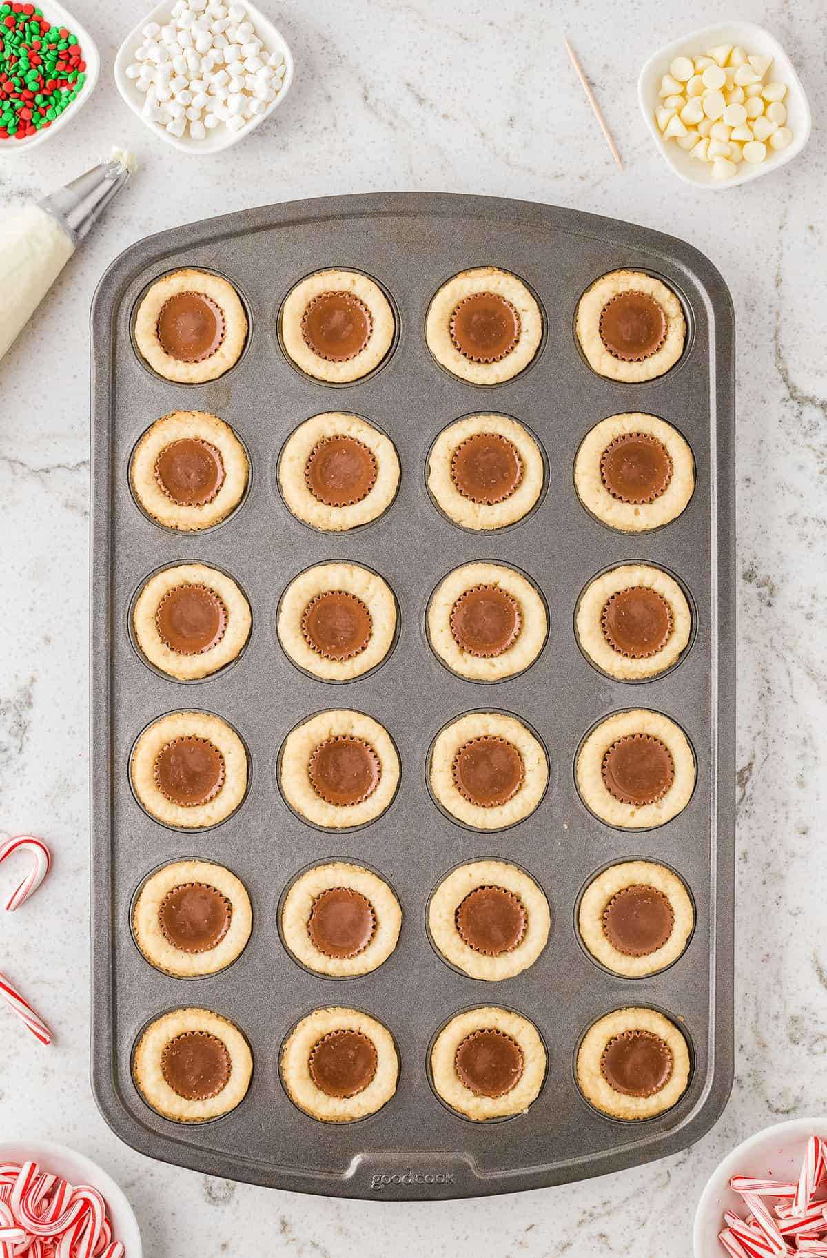 Sugar cookie dough in mini muffin pan with reese's cups in middle