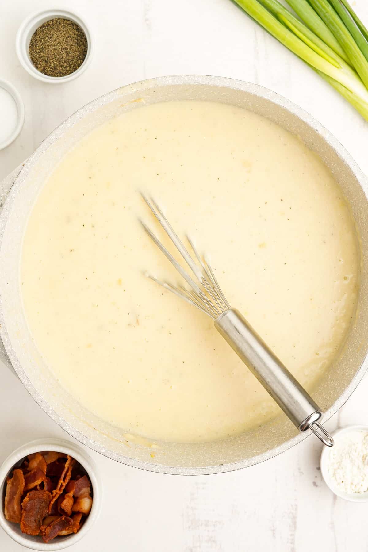 Mashed potato soup in skillet with whisk