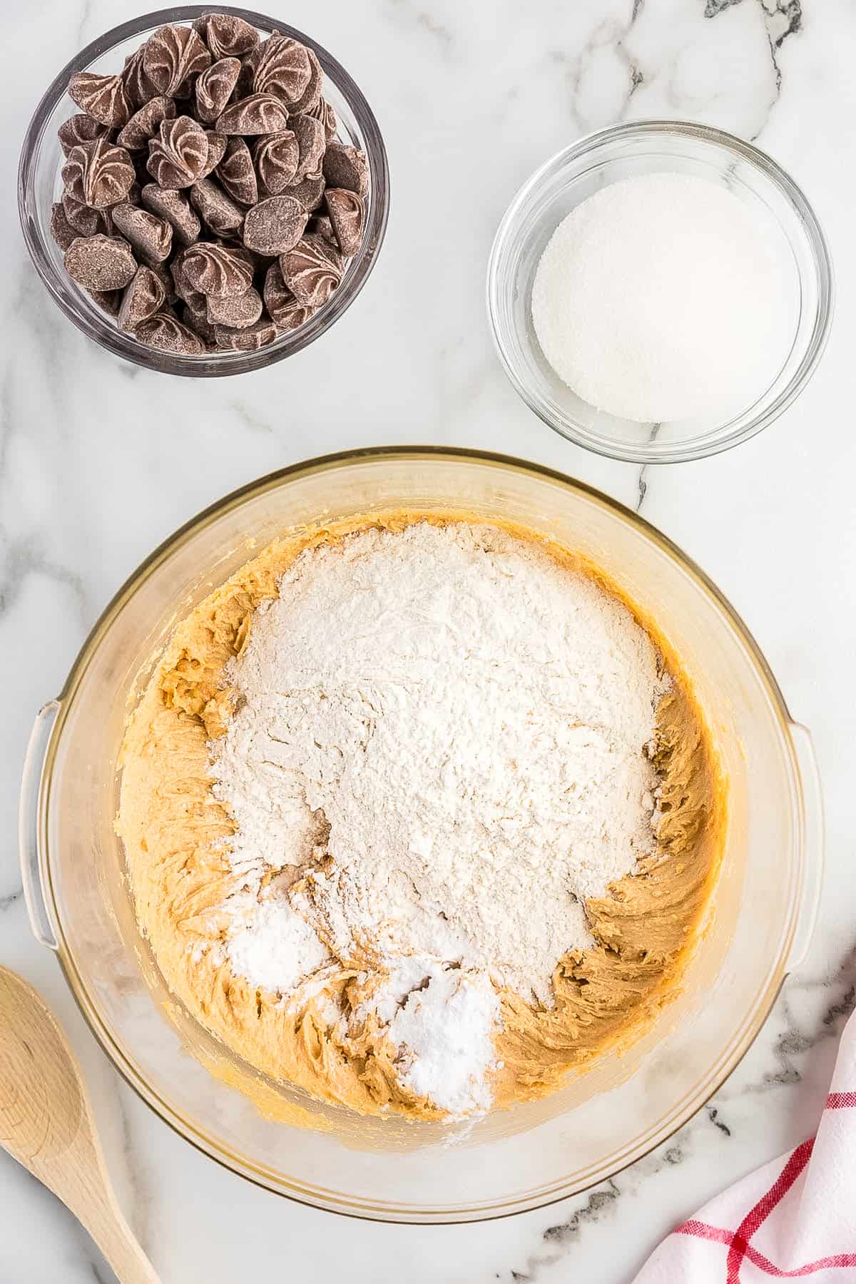 Bowl with creamed together cookie dough adding drying ingredients