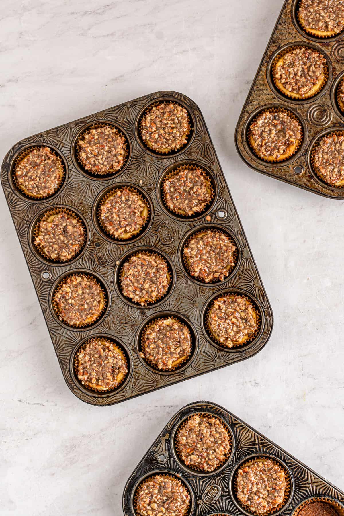 Mini cheesecakes topped with pecan filling in mini muffin pan
