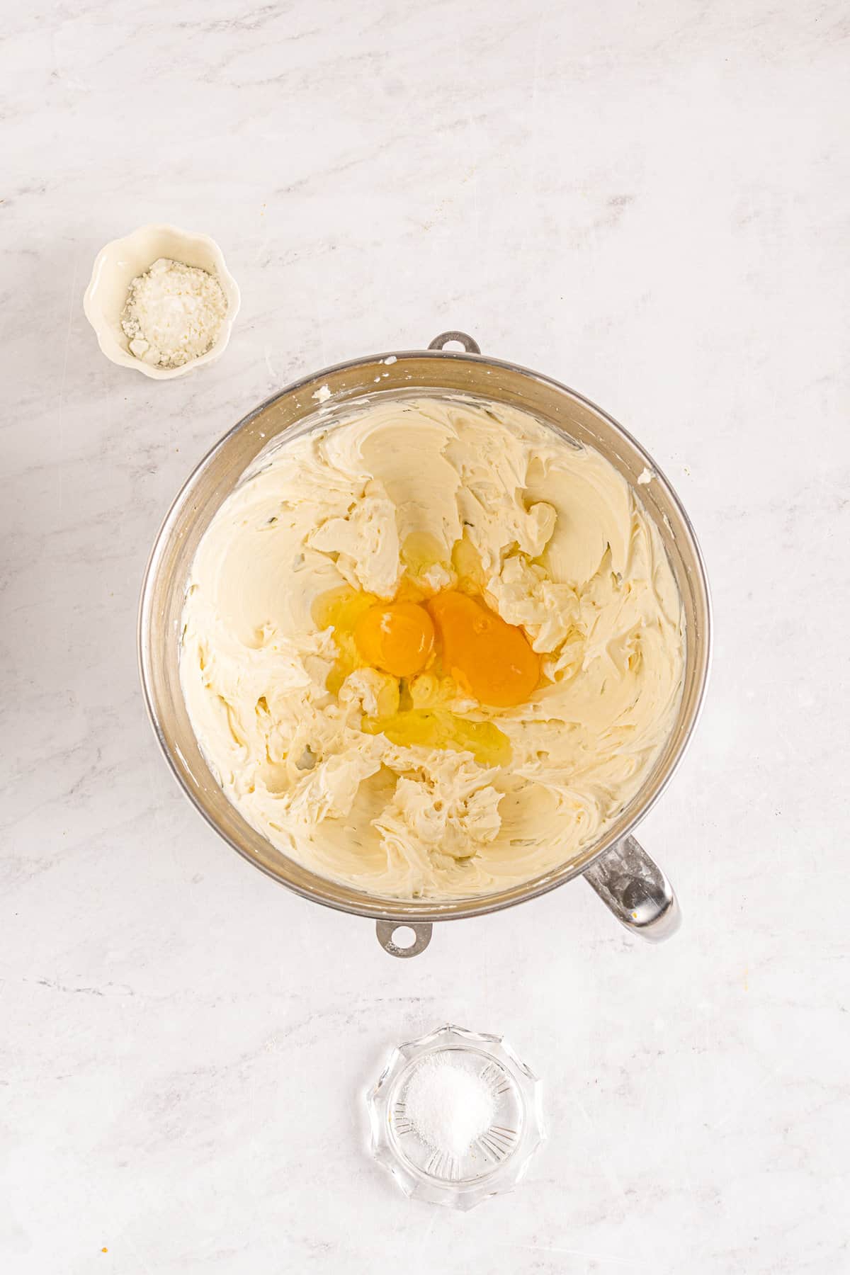 Creamed cream cheese in mixing bowl with eggs