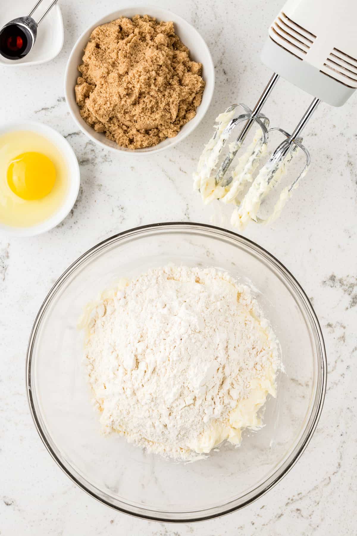 Adding flour to creamed mixture in bowl