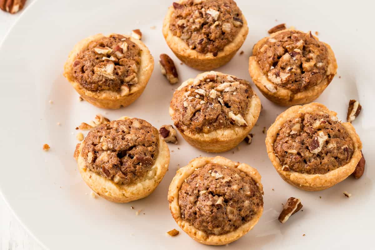 White plate with pecan pie tassies on it