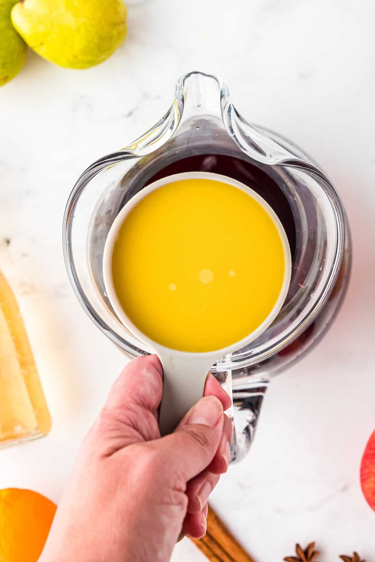 Overhead image of of pouring orange juice into sangria