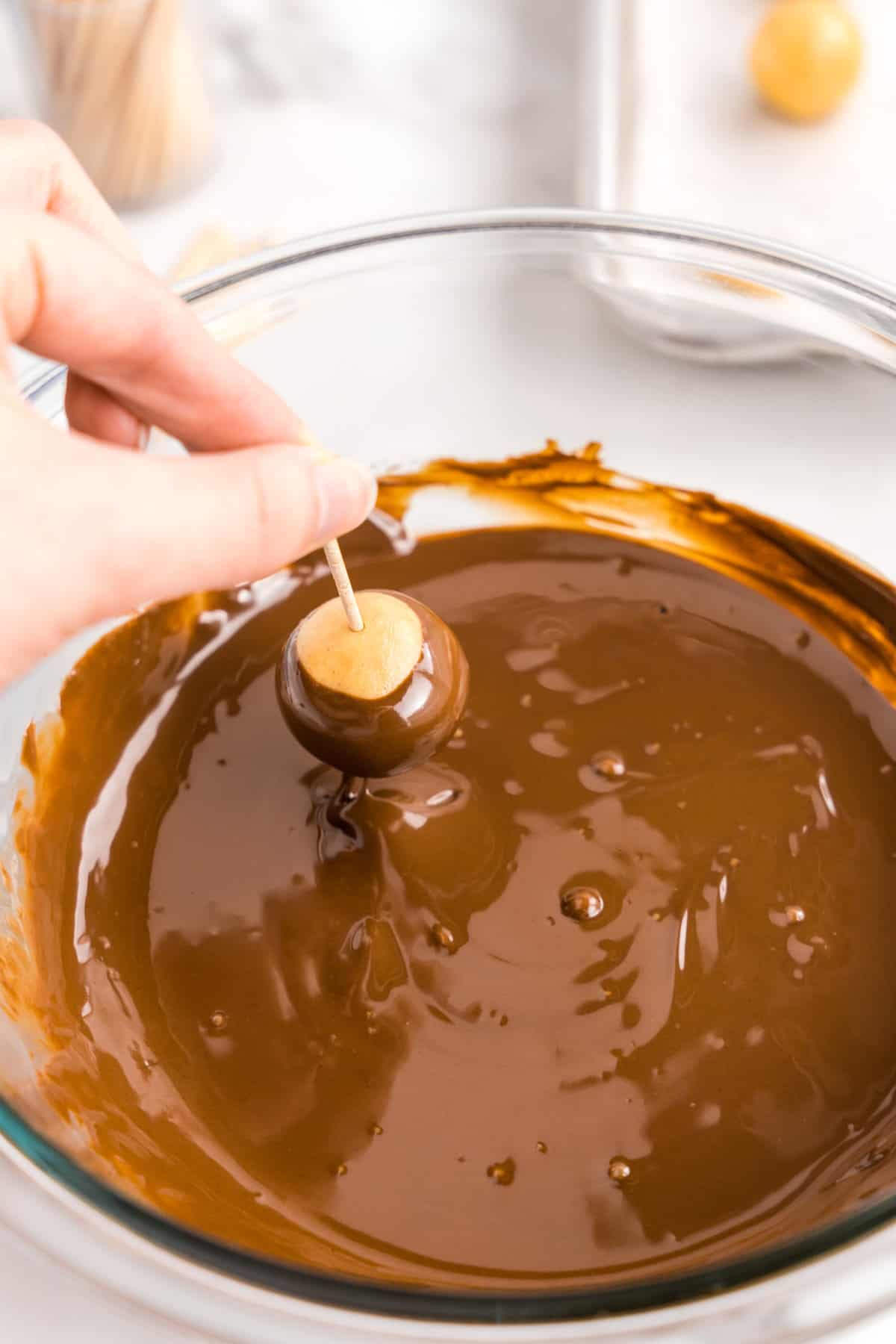 Dipping peanut butter ball in melted chocolate