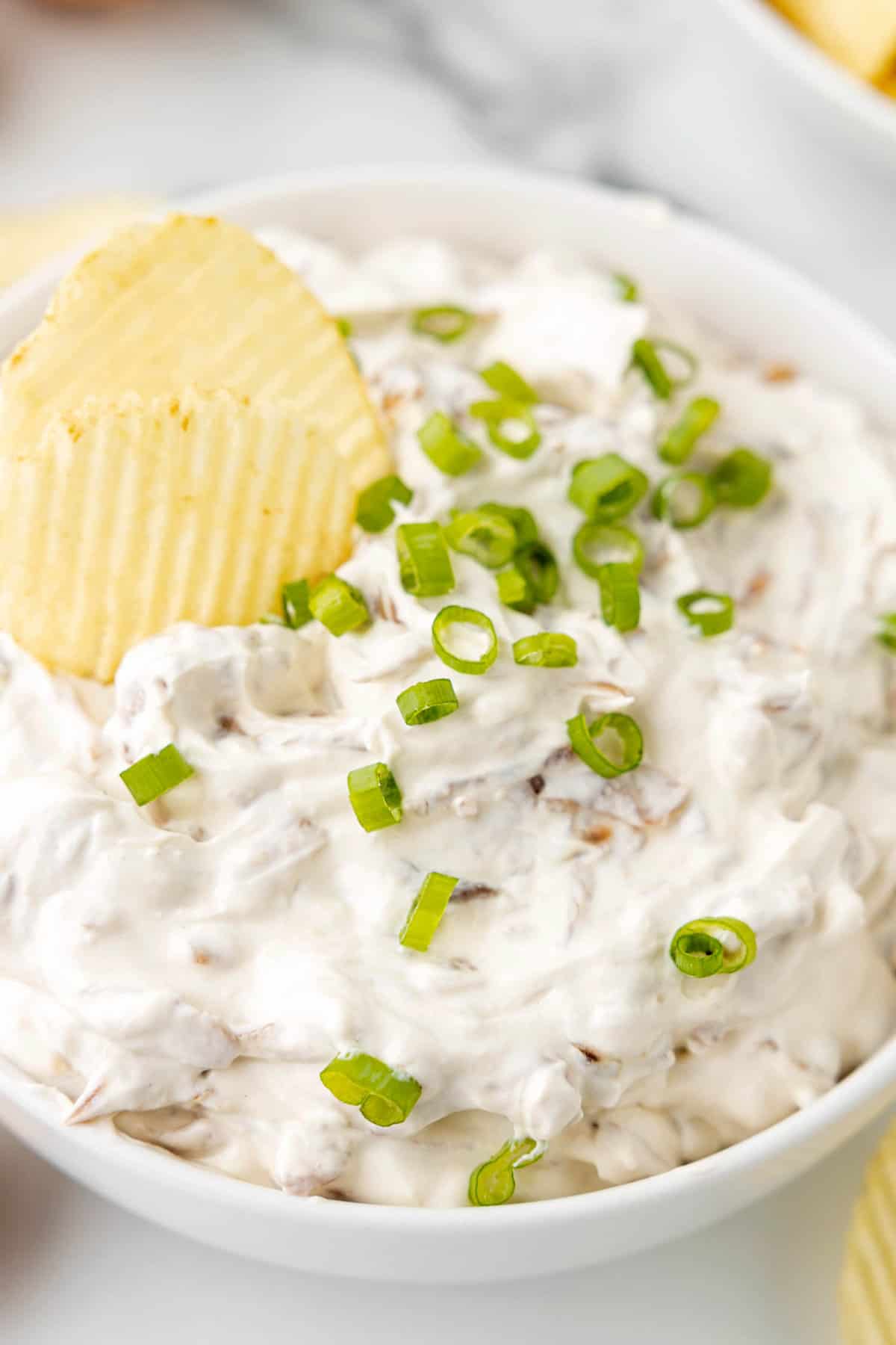 Chip in a bowl of Caramelized Onion Dip