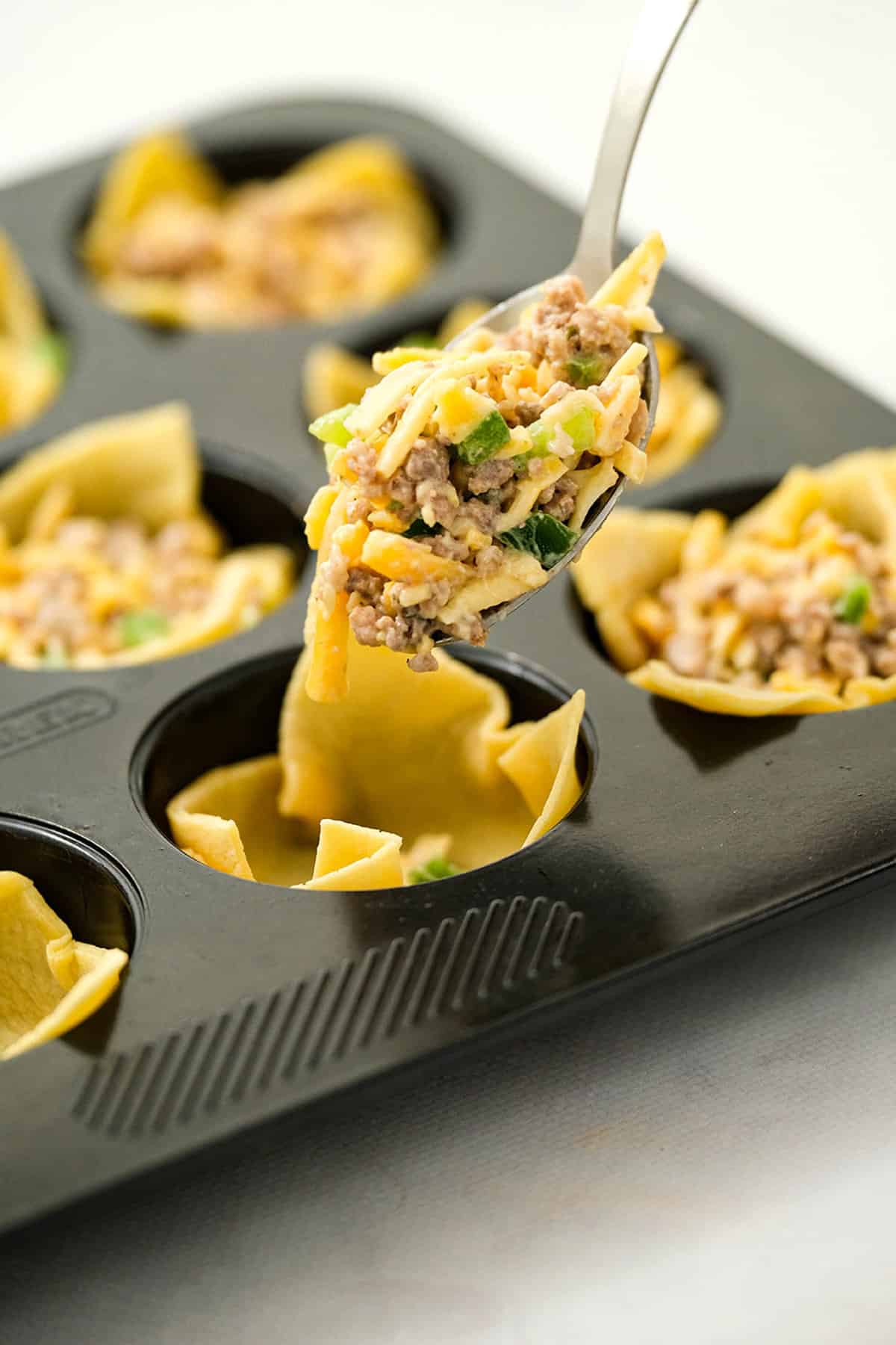 Scooping Sausage Wonton Ingredients into Assembled Wrappers in Muffin Tins