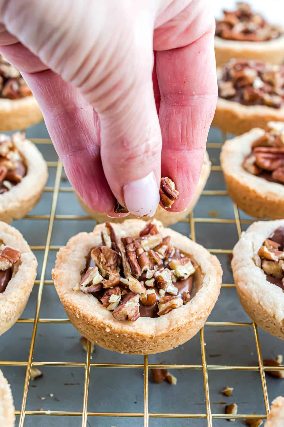 Sprinkling chopped pecans on top of cookie cups