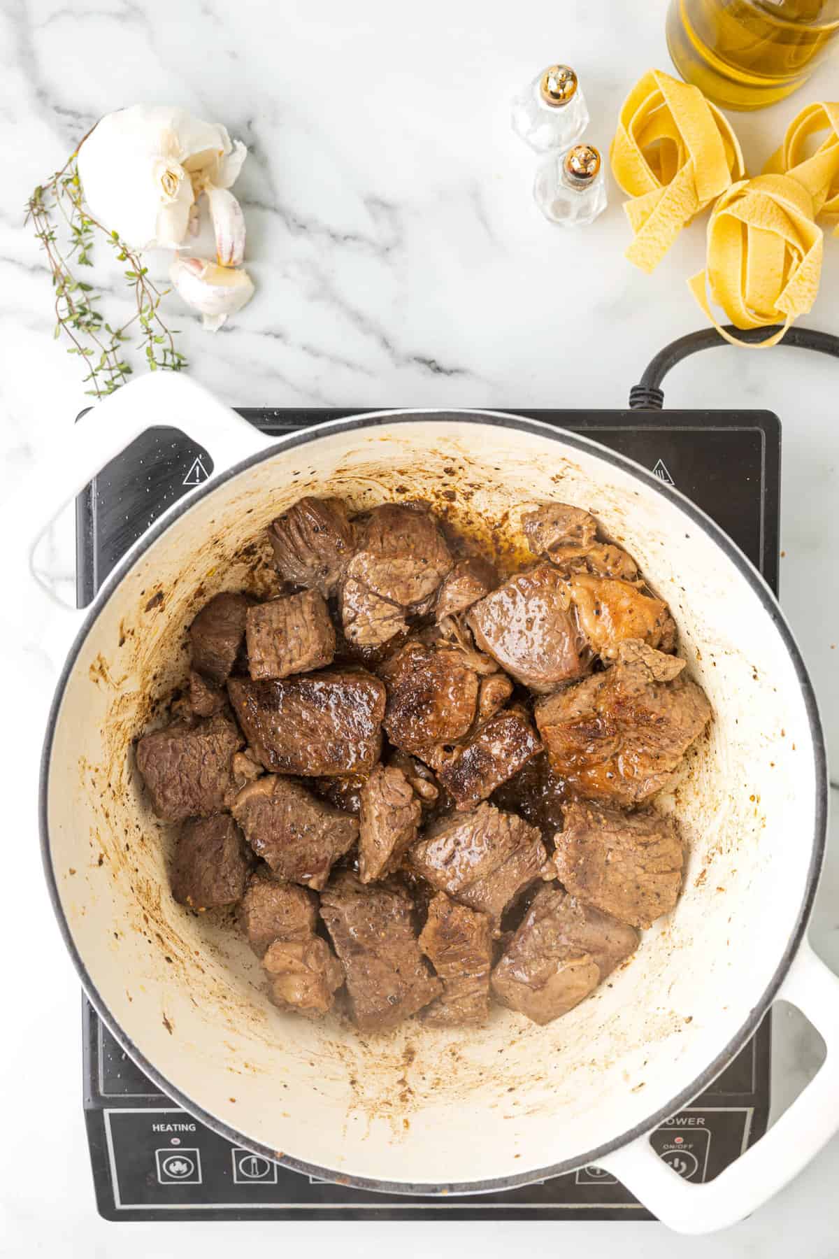 Using Dutch Oven to Sear Seasoned Chuck Roast Cubes for Beef Ragu Recipe