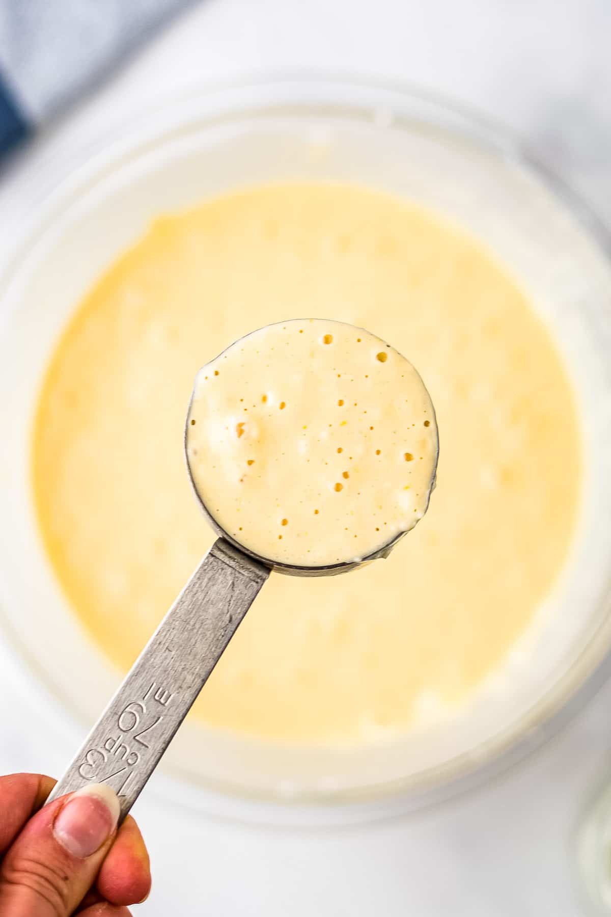 Scooping buttermilk pancake batter with measuring cup