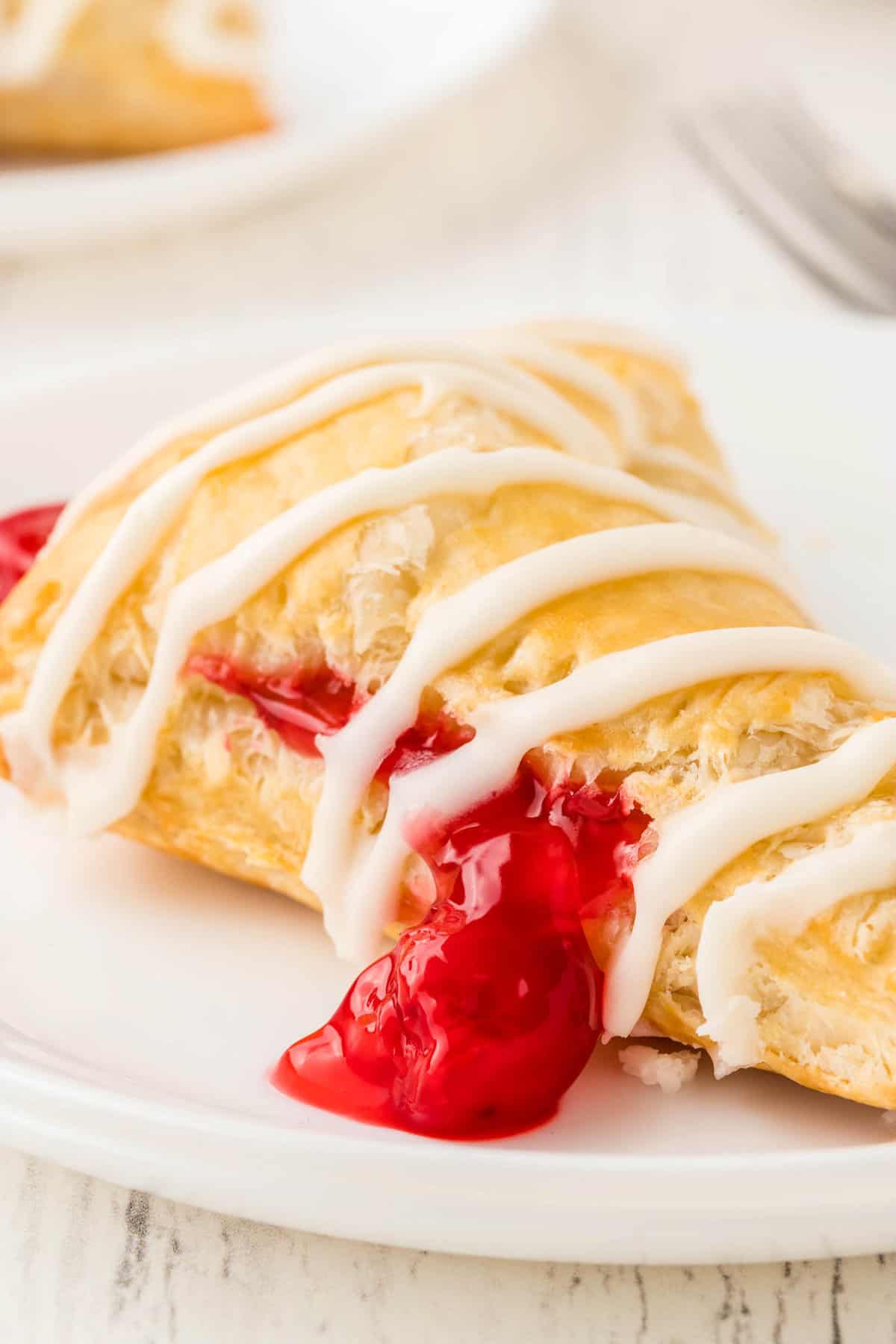 Cherry Turnovers with drizzle of frosting on white plate